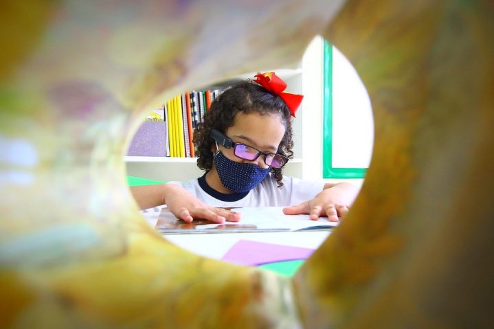 #PraTodosVerem: na imagem podemos ver a estudante Yasmin Venturini de 6 anos lendo um livro com o dispostivo OrCam