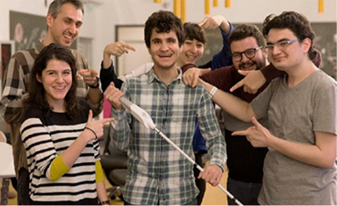 Pessoas felizes abraçam e apontam para jovem segurando uma Bengala Inteligente WeWALK